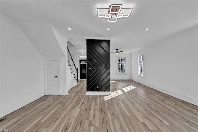 unfurnished living room with ceiling fan, a textured ceiling, and light hardwood / wood-style flooring