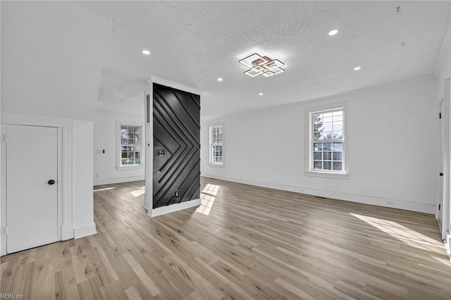 unfurnished living room with a healthy amount of sunlight, a textured ceiling, and light hardwood / wood-style floors