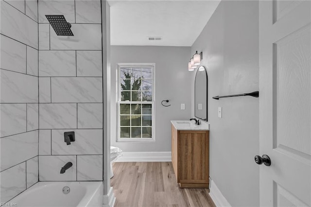 bathroom with tiled shower / bath combo, wood-type flooring, and vanity