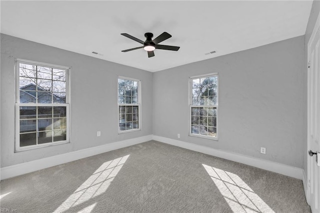 carpeted spare room featuring ceiling fan and a healthy amount of sunlight