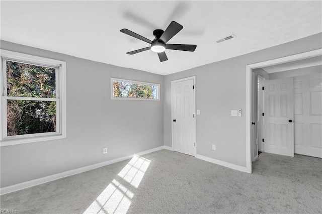 unfurnished bedroom featuring light carpet, ceiling fan, and multiple windows