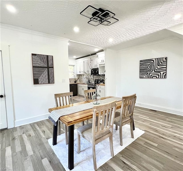 dining room with crown molding, a textured ceiling, and light hardwood / wood-style flooring