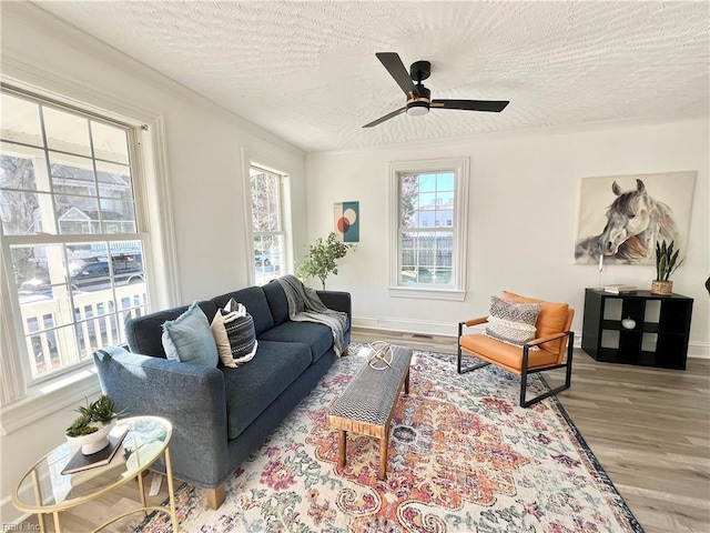 living room with ceiling fan, light wood-type flooring, and a textured ceiling