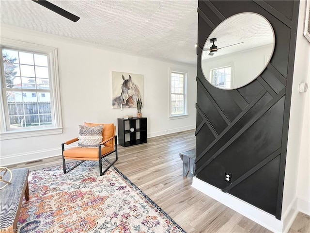 sitting room featuring ceiling fan, a wealth of natural light, and light wood-type flooring