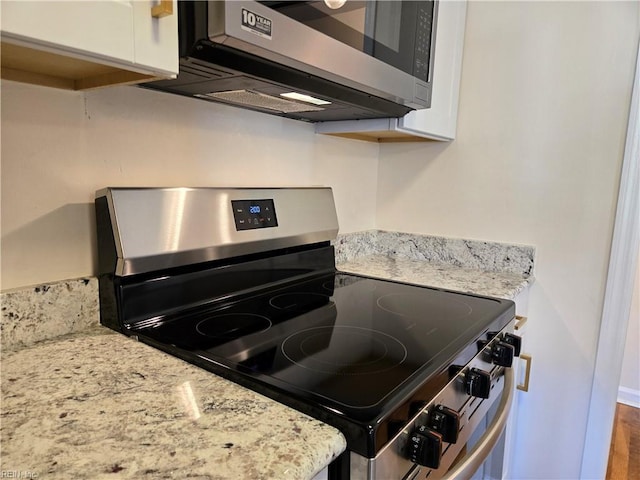 kitchen with white cabinets, light stone countertops, wood-type flooring, and stainless steel appliances