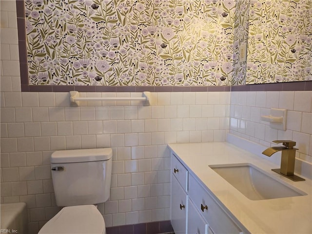 bathroom featuring vanity, toilet, and tile walls