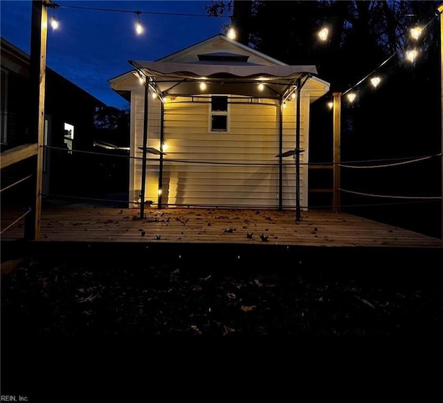 property exterior at night with a wooden deck