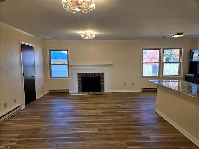 unfurnished living room featuring dark hardwood / wood-style floors, baseboard heating, and a brick fireplace