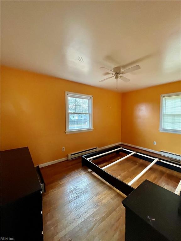 unfurnished bedroom with hardwood / wood-style floors, ceiling fan, and a baseboard radiator