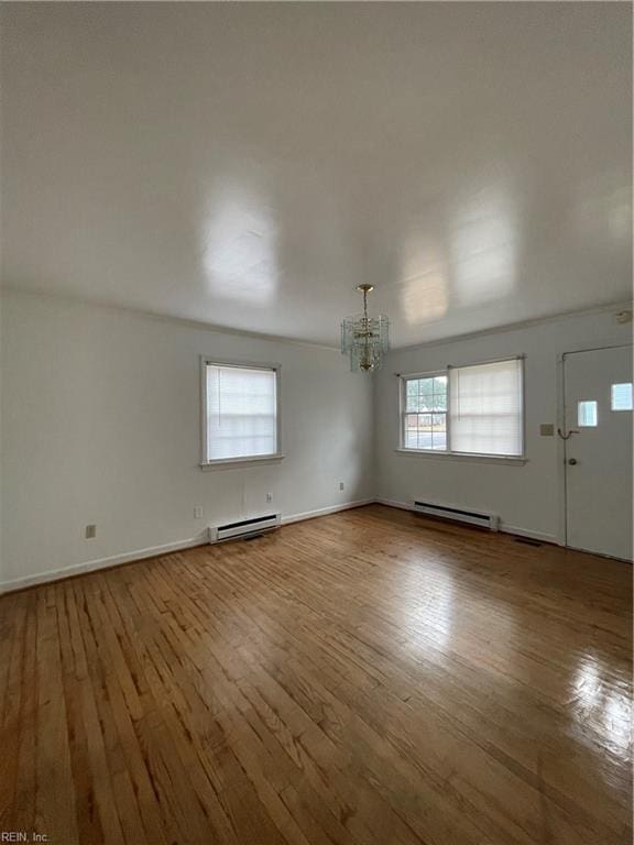 interior space featuring wood-type flooring, baseboard heating, and a chandelier