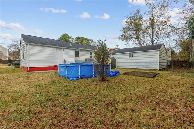 rear view of house with a fenced in pool and a lawn