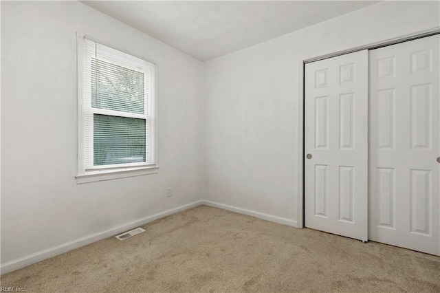 unfurnished bedroom featuring a closet and light colored carpet