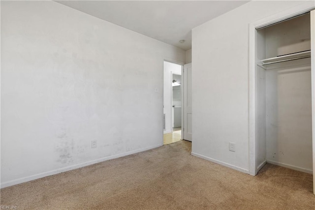 unfurnished bedroom with light carpet and a closet