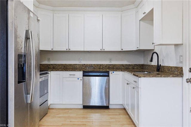 kitchen with dark stone countertops, sink, white cabinetry, and stainless steel appliances