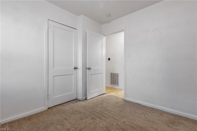 unfurnished bedroom with light carpet and a closet