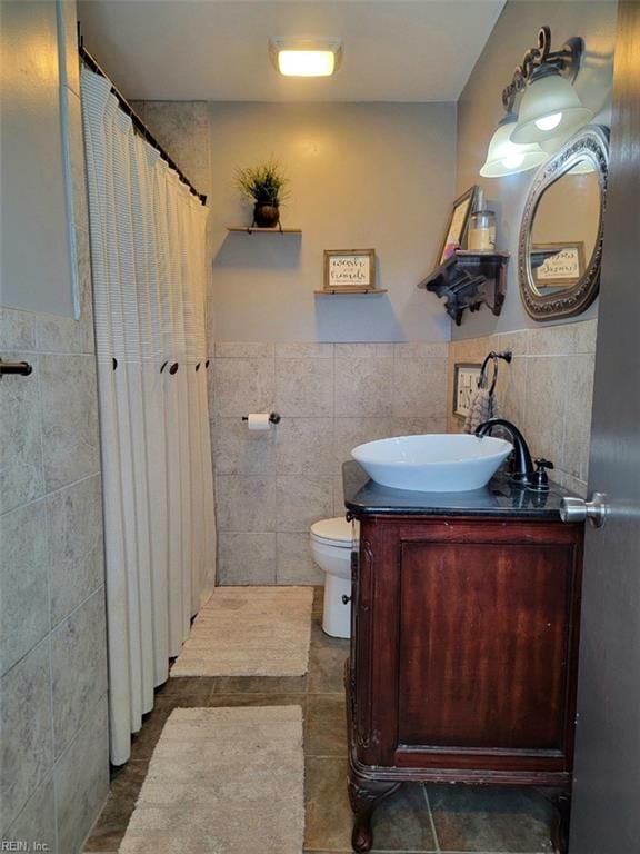 bathroom featuring vanity, toilet, tile walls, and walk in shower