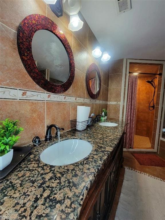 bathroom featuring vanity, a tile shower, tile walls, and tasteful backsplash