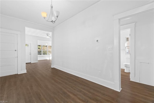 unfurnished dining area featuring ceiling fan with notable chandelier, dark hardwood / wood-style flooring, and crown molding