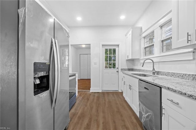 kitchen featuring white cabinets, appliances with stainless steel finishes, light stone countertops, and sink