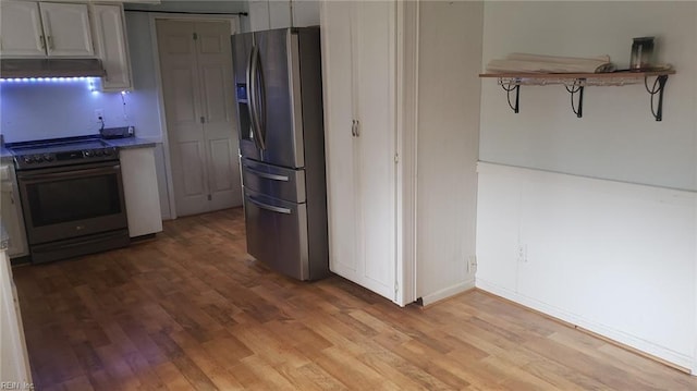 kitchen featuring electric range oven, stainless steel refrigerator with ice dispenser, and light hardwood / wood-style flooring