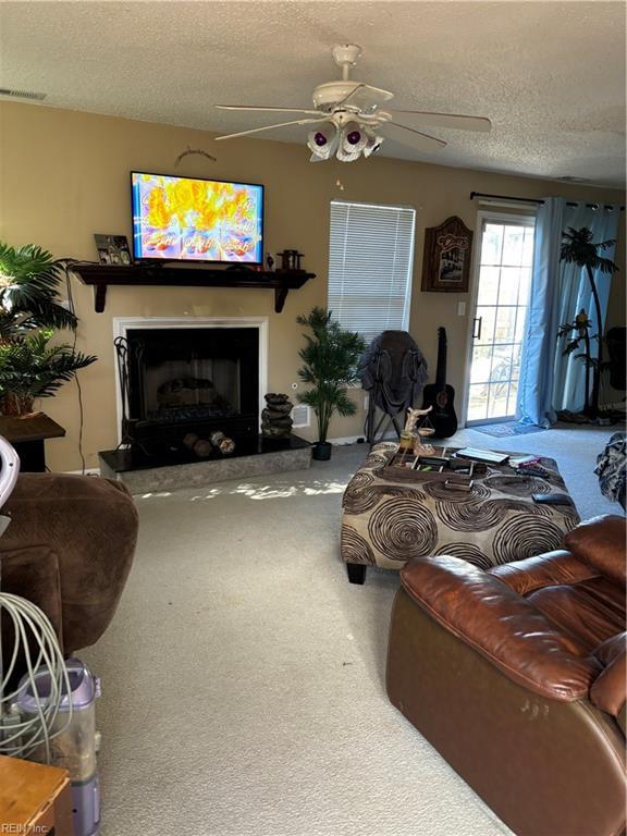 carpeted living room with ceiling fan and a textured ceiling