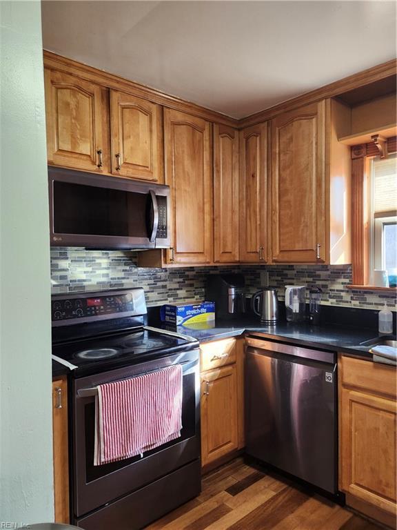 kitchen with tasteful backsplash, dark wood-type flooring, and appliances with stainless steel finishes