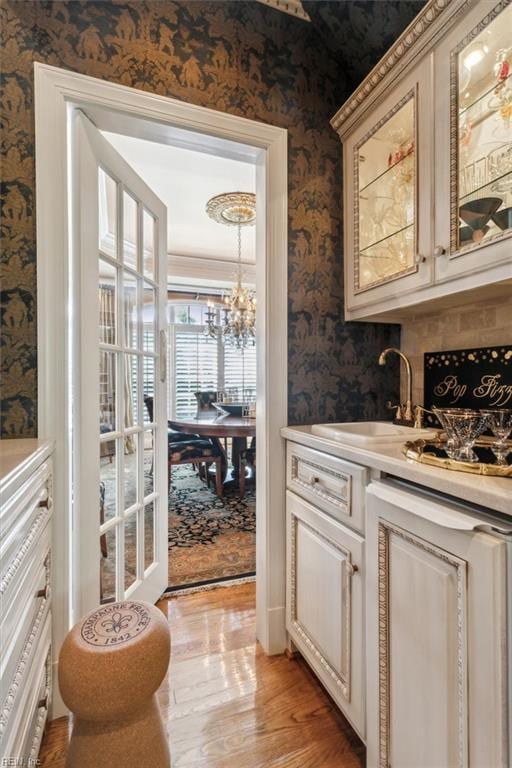 bar featuring crown molding, sink, and light hardwood / wood-style floors