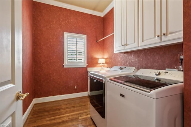 clothes washing area featuring ornamental molding, hardwood / wood-style floors, cabinets, and independent washer and dryer