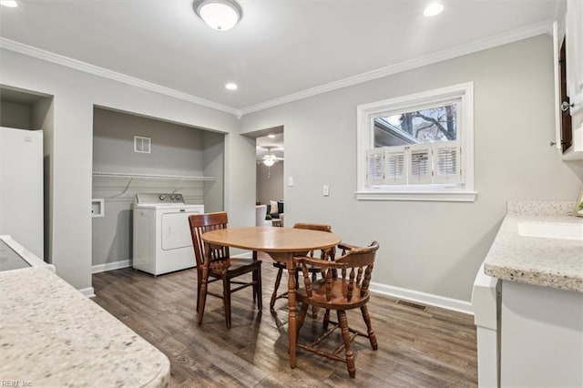 dining space with washer / dryer, ornamental molding, sink, and dark wood-type flooring