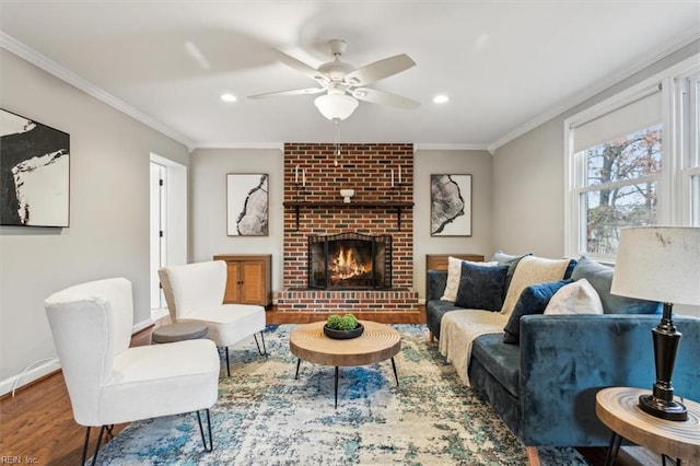 living room featuring crown molding, a fireplace, ceiling fan, and hardwood / wood-style floors