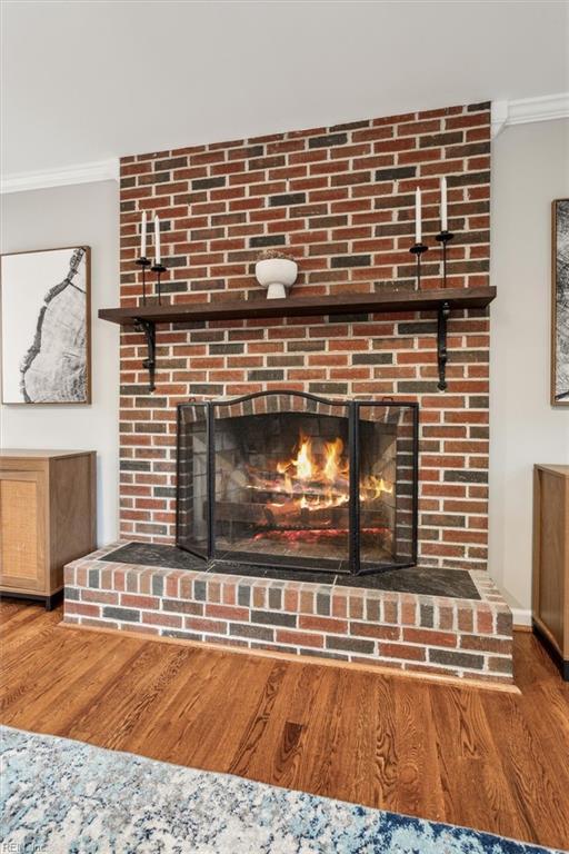 room details with wood-type flooring, crown molding, and a brick fireplace