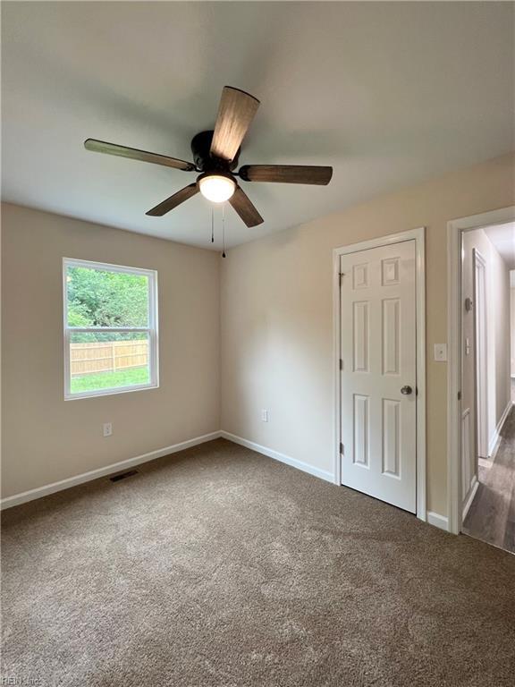 spare room with ceiling fan and dark carpet