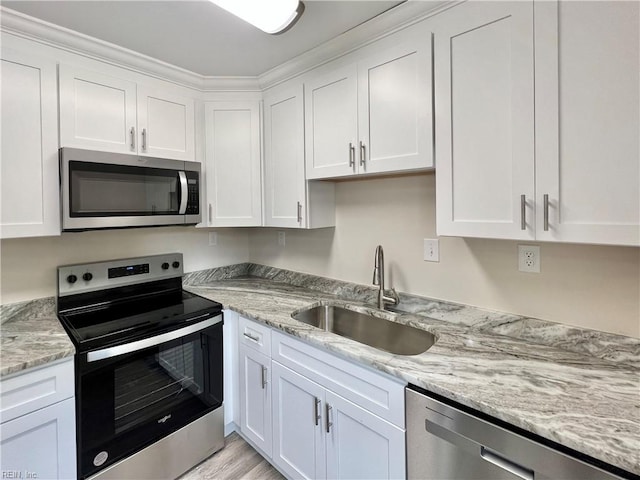 kitchen featuring light stone countertops, stainless steel appliances, crown molding, sink, and white cabinets