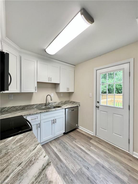 kitchen featuring white cabinetry, sink, light stone counters, stainless steel dishwasher, and range