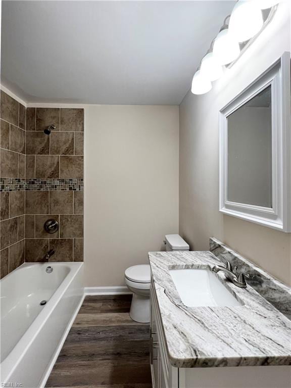 full bathroom with vanity, wood-type flooring, tiled shower / bath combo, and toilet