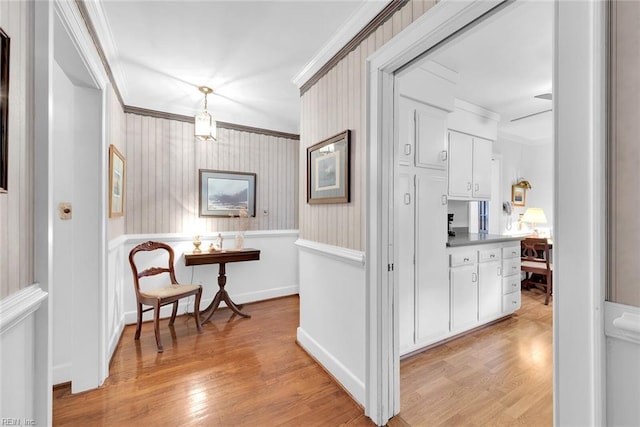 hall with light hardwood / wood-style floors and crown molding