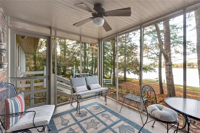 sunroom featuring ceiling fan, a water view, and a healthy amount of sunlight