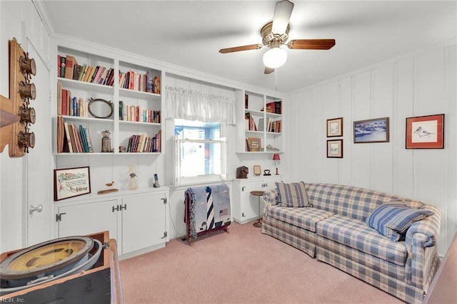 living area with crown molding, ceiling fan, and light colored carpet