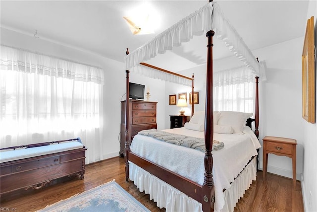 bedroom with multiple windows and dark hardwood / wood-style flooring