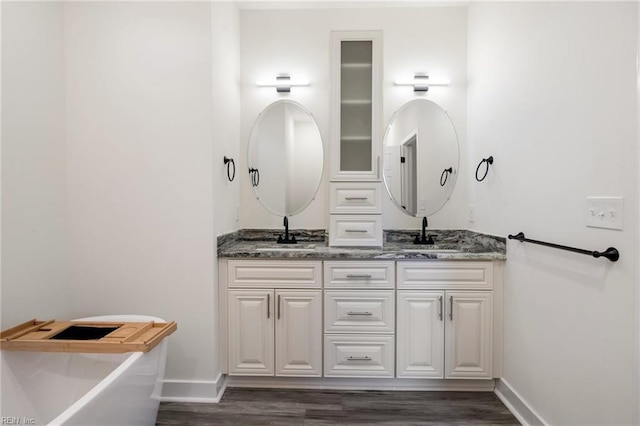 bathroom with wood-type flooring, vanity, and a tub to relax in