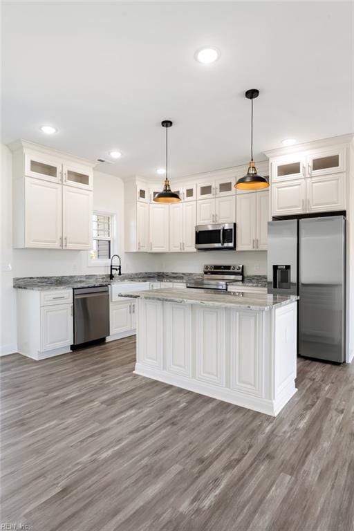 kitchen with decorative light fixtures, stainless steel appliances, and white cabinetry