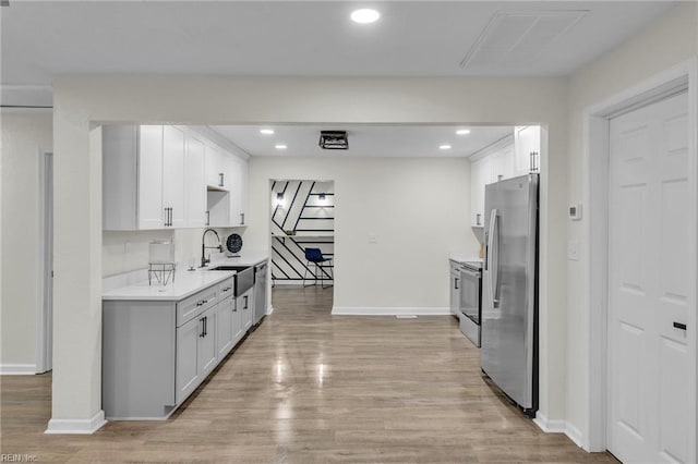 kitchen featuring appliances with stainless steel finishes, light wood-type flooring, white cabinetry, and sink