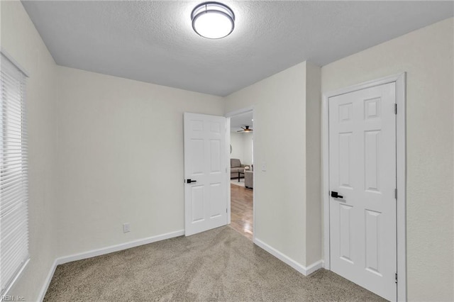 spare room featuring a textured ceiling, ceiling fan, and light carpet