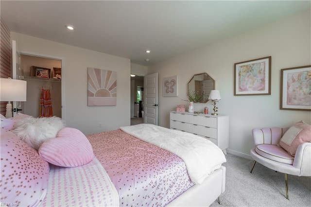 bedroom with a walk in closet, a closet, and light colored carpet