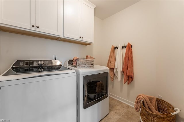 clothes washing area with cabinets and washing machine and dryer