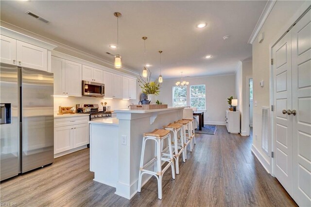 kitchen with white cabinetry, a center island, hanging light fixtures, and appliances with stainless steel finishes