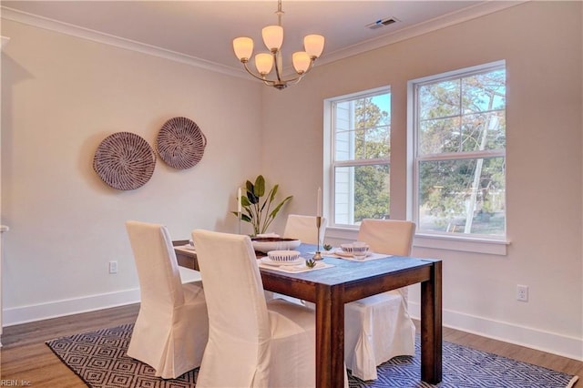 dining room with a notable chandelier, dark hardwood / wood-style flooring, and ornamental molding