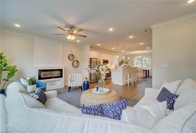 living room featuring ceiling fan, a fireplace, dark wood-type flooring, and ornamental molding