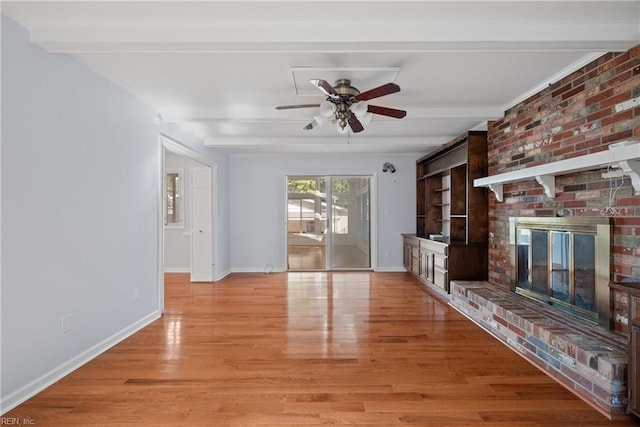 unfurnished living room featuring ceiling fan, light hardwood / wood-style flooring, beamed ceiling, and a brick fireplace