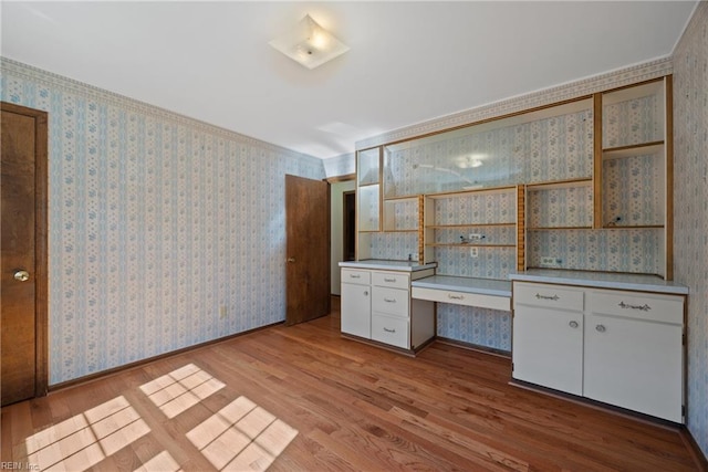 interior space featuring white cabinets, light wood-type flooring, and ornamental molding